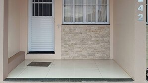 Una entrada de edificio con una puerta cerrada, una ventana con barrotes y un muro de piedra.
