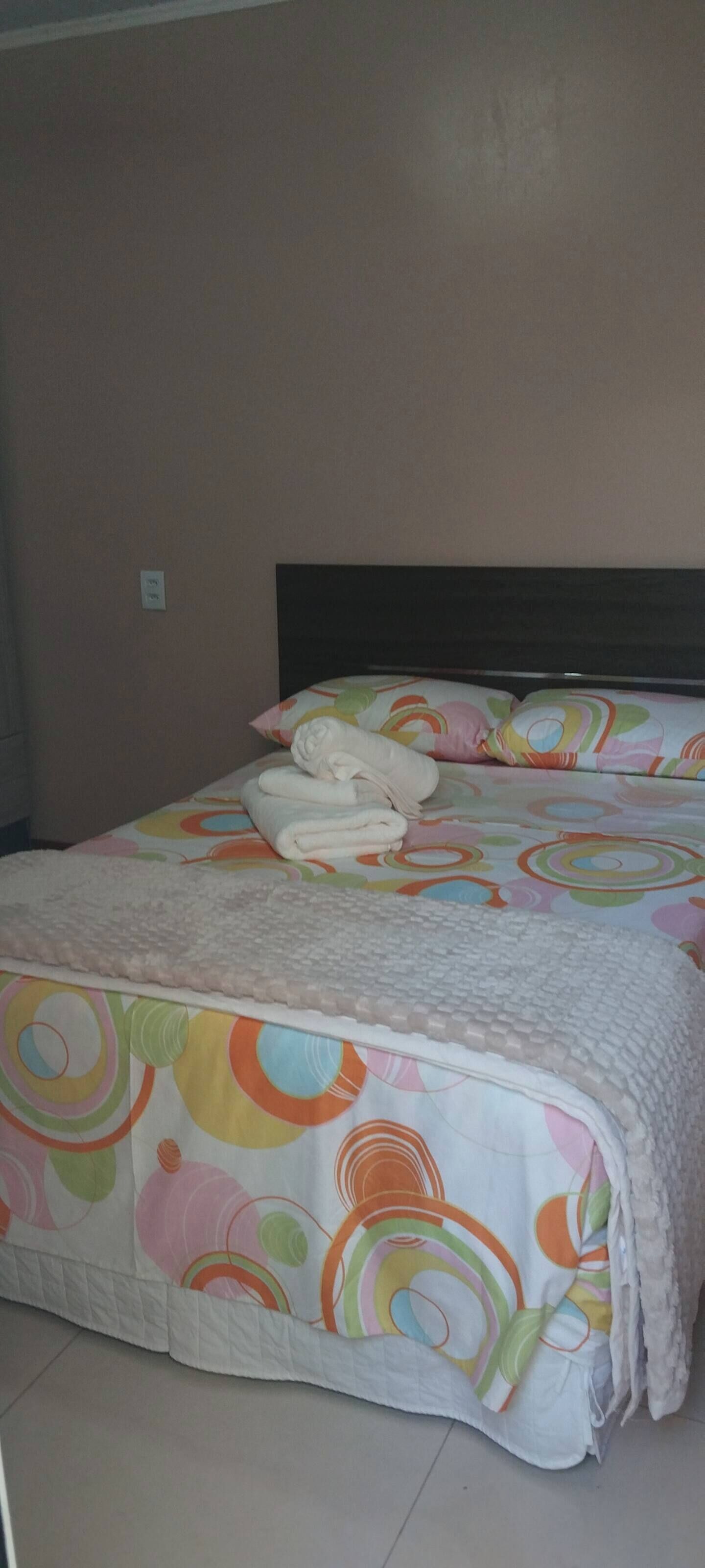 Un lit recouvert d’une courtepointe aux motifs circulaires et colorés, et agrémenté de draps blancs.