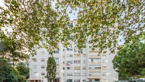Un edificio residencial de varios pisos con un estacionamiento al frente.