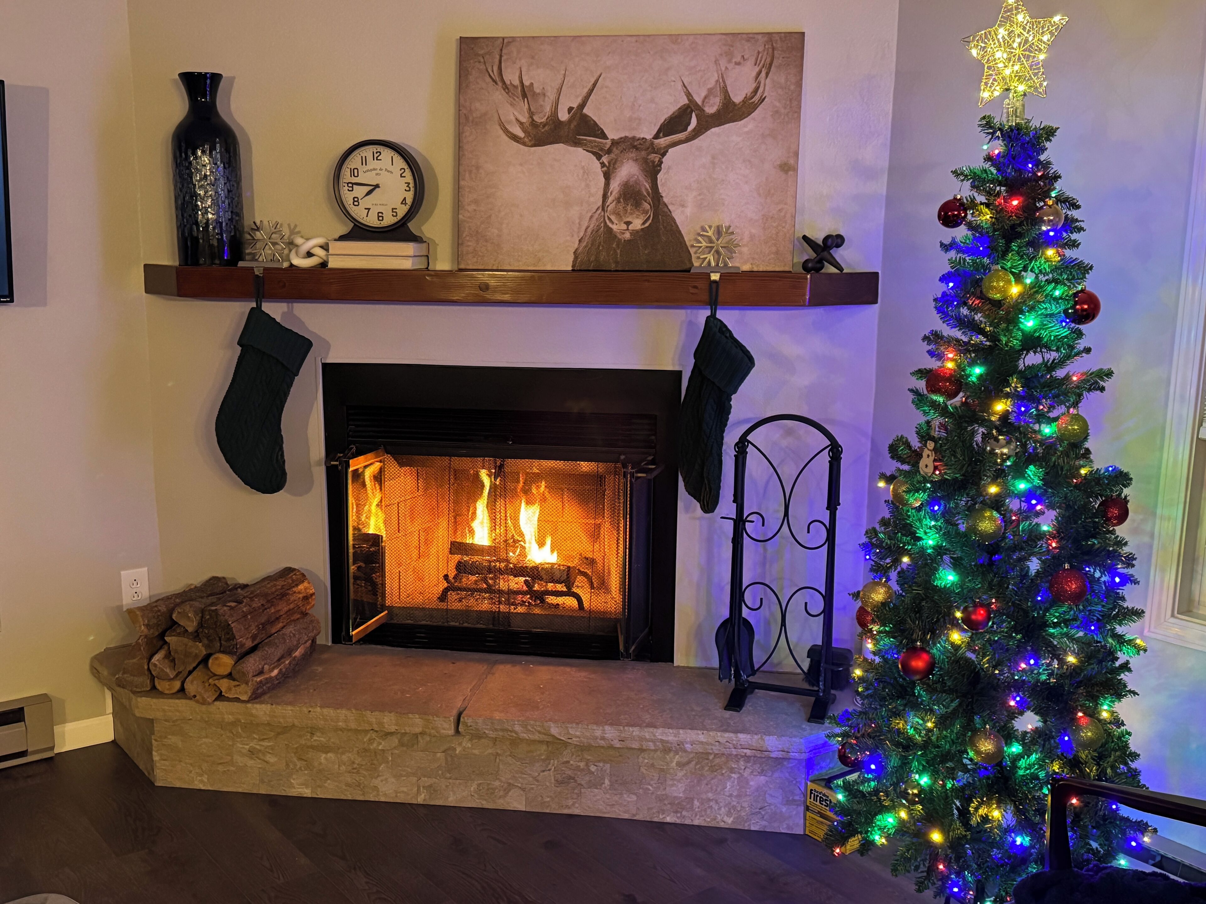 A fireplace with a Christmas tree decorated with colorful lights and ornaments.