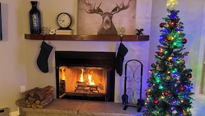 Ein Kamin mit Weihnachtsbaum, geschmückt mit bunten Lichtern und Verzierungen.