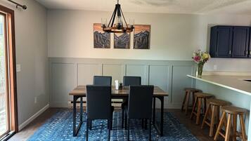 A dining area with a wooden table, black chairs, a blue patterned rug, and a chandelier.