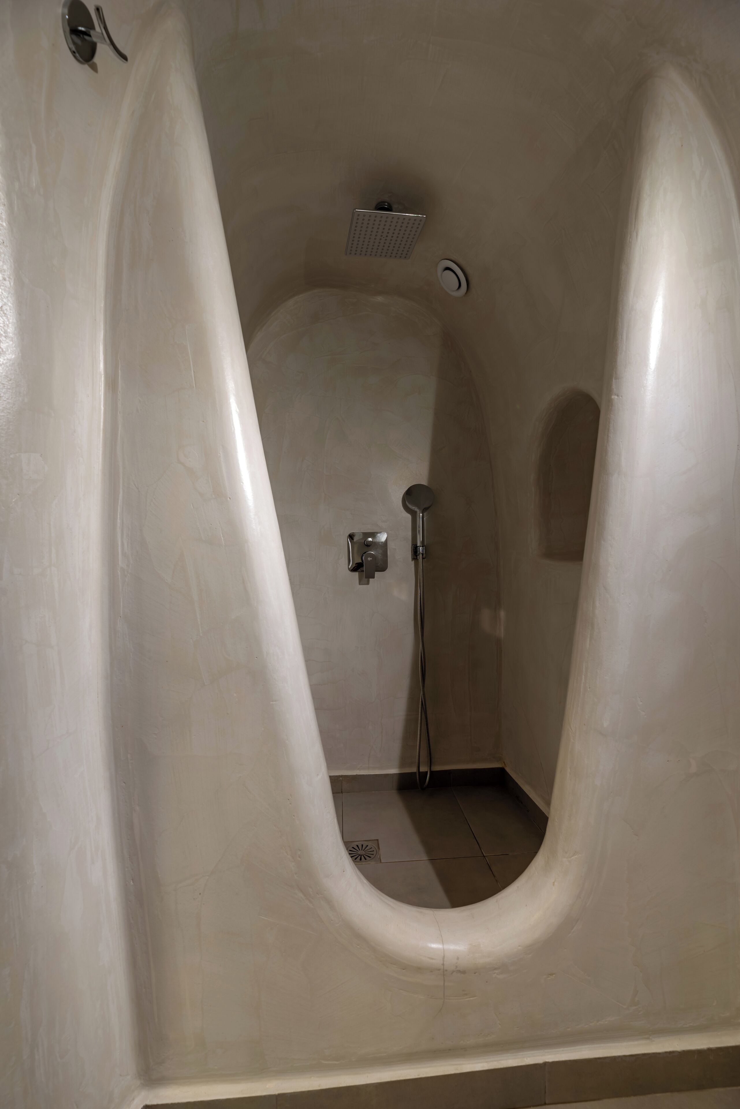 A bathroom with a unique bathtub design, a showerhead, and a toilet.