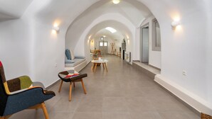 Un vaste hall d’entrée doté d’un haut plafond et de voûtes en arc, qui mène à un espace repas avec une table et des chaises.