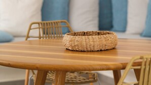 Une table de salle à manger en bois, surmontée d’un panier tressé au centre, entourée de chaises en osier.