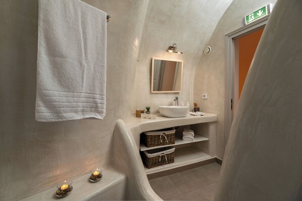A bathroom with a white sink, mirror, and towel hanging on the wall. There are baskets and shelves below the sink.