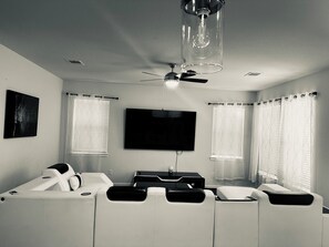 Relax in this stylish living room with a flat-screen TV, ceiling fan, and comfortable seating area.
