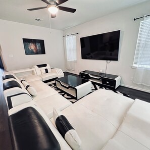 Relax in a spacious living room with a large flat-screen TV, comfortable sofas, and a functional layout.