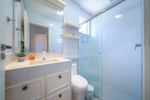 Een moderne badkamer met een douchecabine van glas, een wit wastafelmeubel met spiegel, en een toilet.