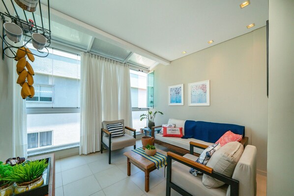 A modern living room with a sofa, chairs, a coffee table, and a large window with curtains.