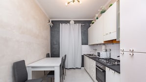 Una cocina compacta con zona de comedor, que incluye una mesa blanca, sillas, estufa y armarios.