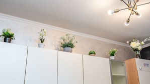 Una cocina con armarios blancos, un mueble de madera y plantas en macetas sobre la encimera.