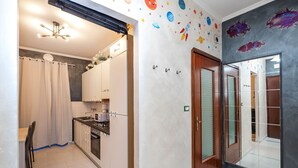 Una cocina moderna con armarios blancos, horno integrado y comedor con sillas.