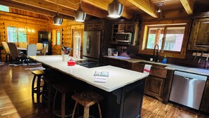A log cabin-style kitchen with a large island, wooden floors, and modern appliances.