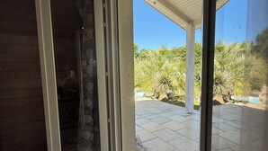 Ein Zimmer mit einer Schiebetür zu einer Terrasse im Freien, mit gefliestem Boden und einem gemusterten Teppich.