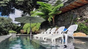 Une piscine aux eaux cristallines, dotée de chaises longues et d’un parasol.