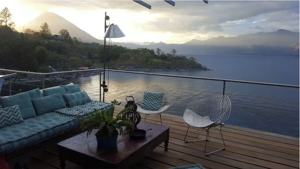 Une terrasse avec un canapé, des chaises et une table agrémentée d’une plante.