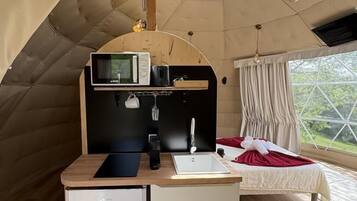 A cozy tent with a kitchenette, a bed, and a large skylight.