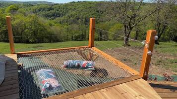 Un pontile in legno con un'area trampolino protetta da una rete e due sacchi di palle sportive.