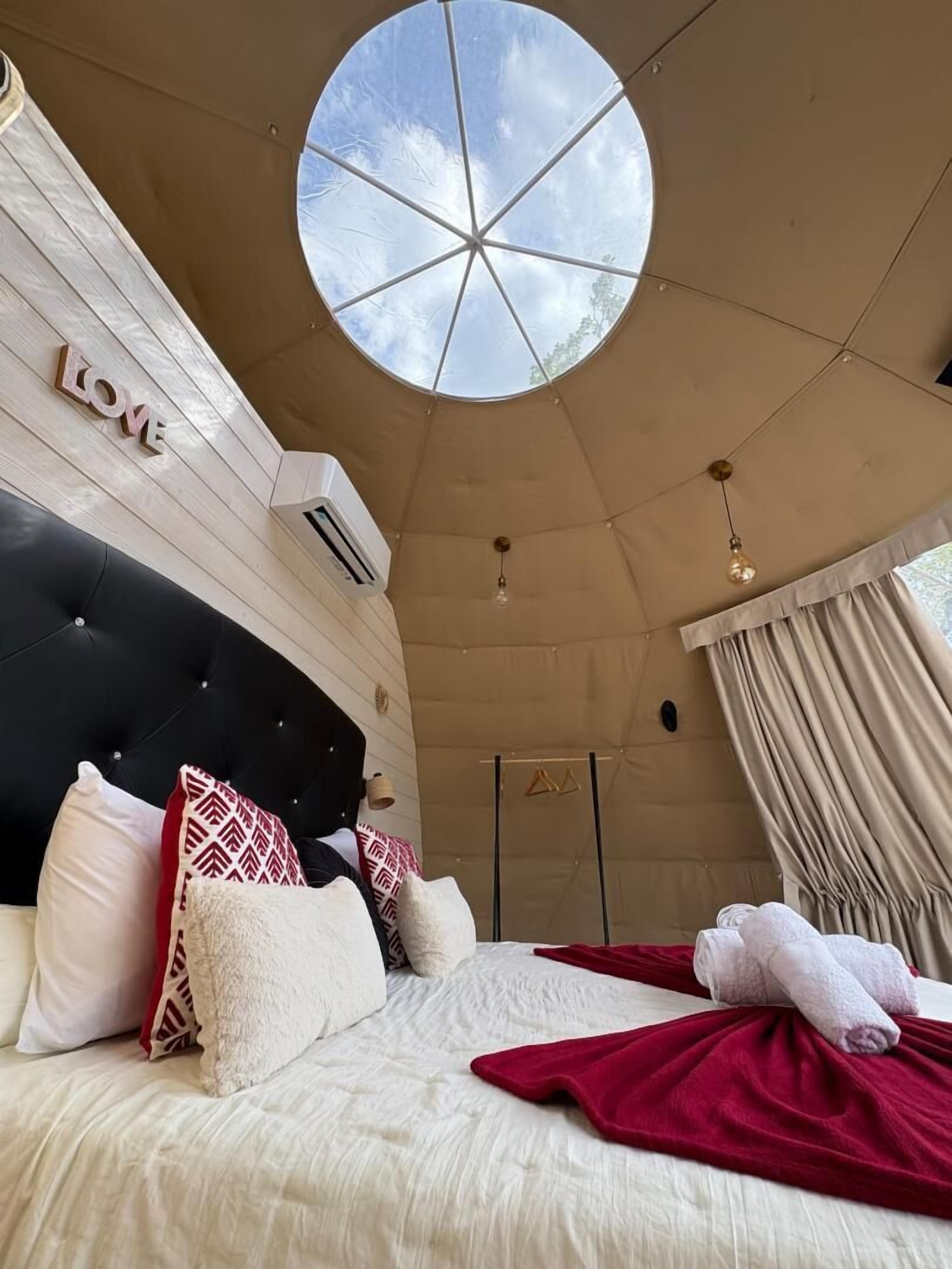 A bedroom with a large bed, a circular skylight, and a 'LOVE' sign on the wall.
