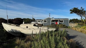 Et hus med rødlakeret dør, veranda og en båd i forgrunden.