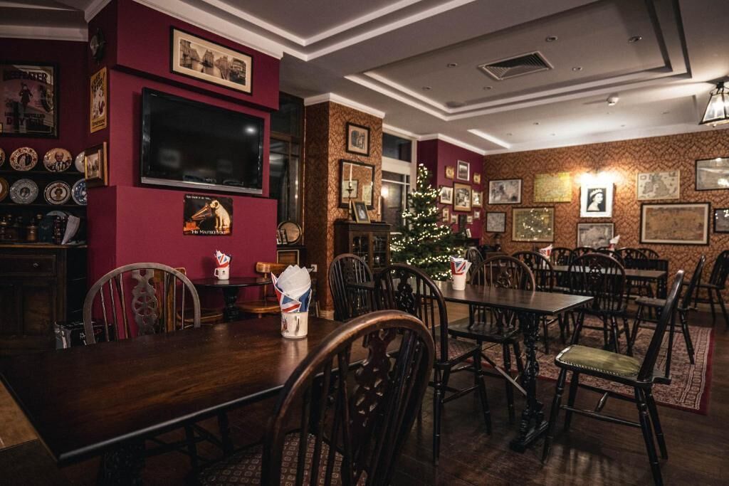 A dining area with a large wooden table, multiple chairs, and a Christmas tree.