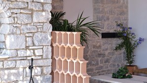 A stone wall with a built-in planter, a bench, and a tiled floor. - Anchorage Paros  (Piso Livadi)