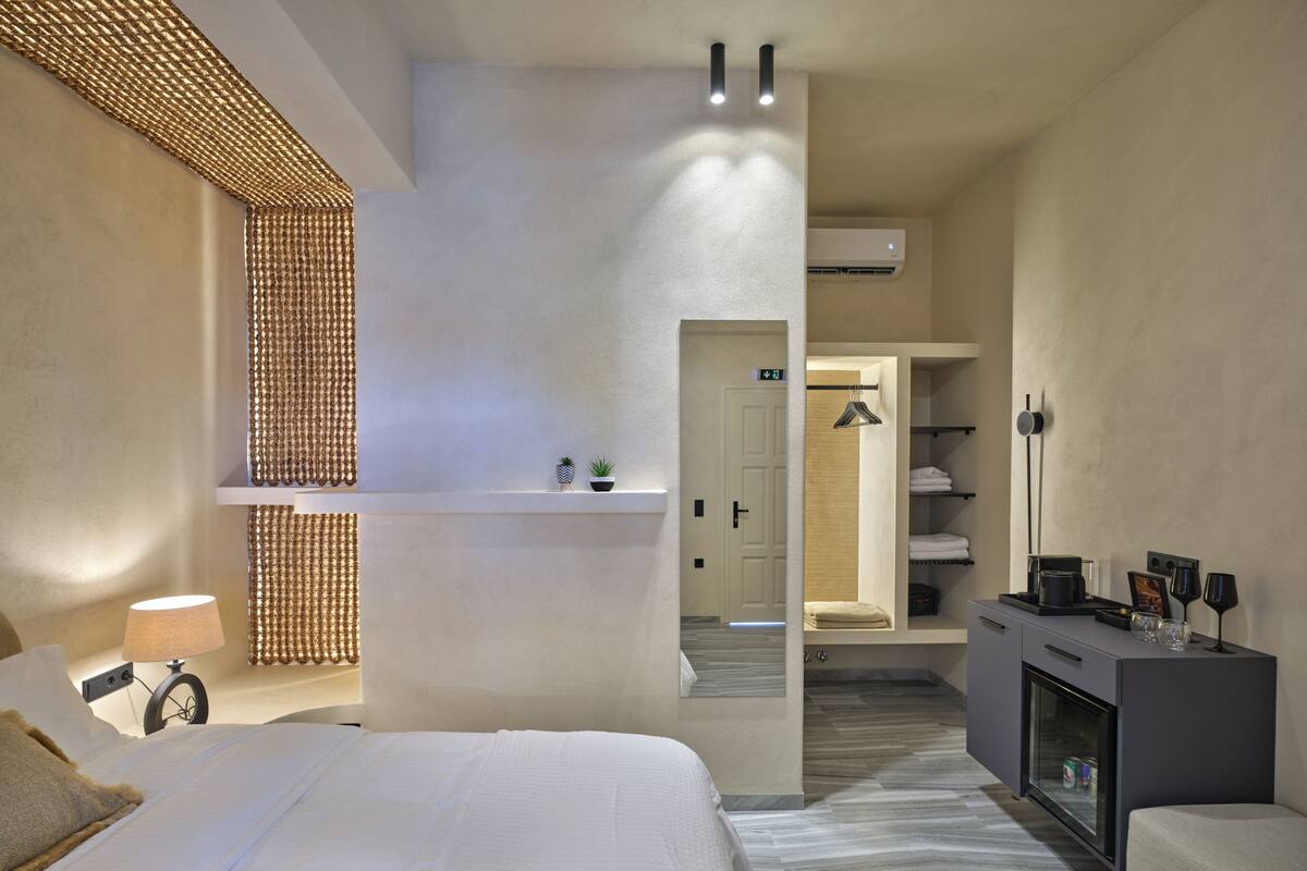 Une chambre d’hôtel moderne dotée d’un grand lit, d’une table de chevet avec une lampe, d’une armoire et d’un coin salon avec une petite table et des chaises.