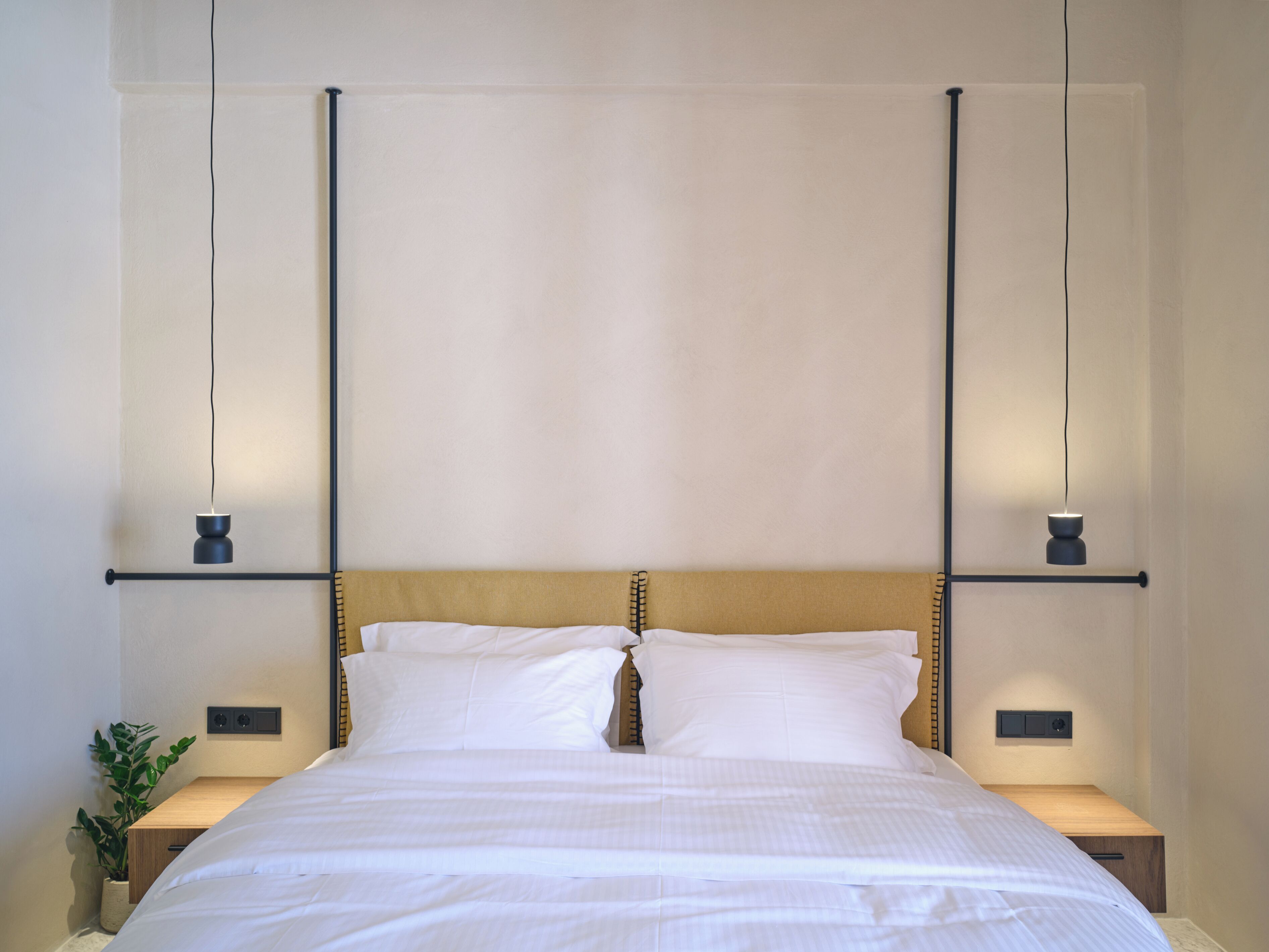 A neatly made bed with white linens, two bedside tables with lamps, and a wall-mounted shelf above the bed.