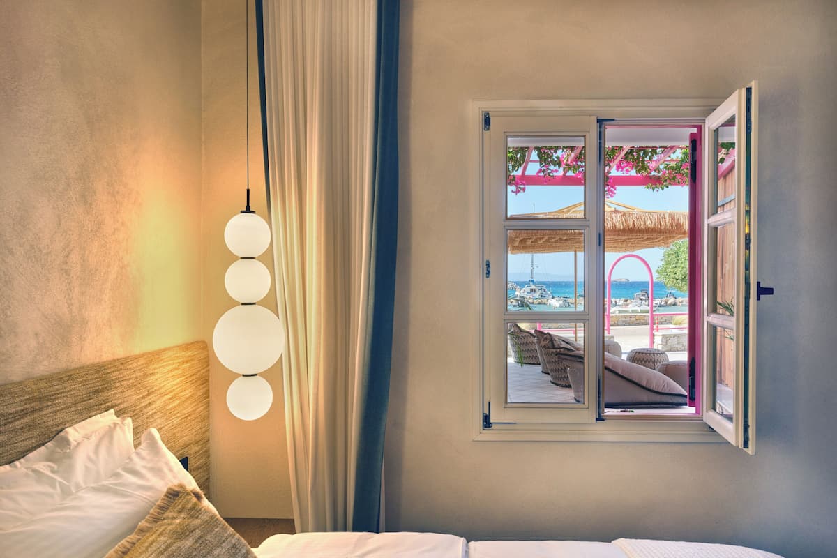 Une chambre à coucher avec un lit, une fenêtre donnant sur la mer et un luminaire suspendu.