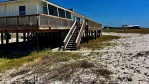 A beachfront house with a wooden deck and a staircase leading to the entrance. - Pet-Friendly Gulf Front Escape nestled in the Dunes (Dauphin Island)