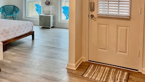 A spacious room with a bed, a ceiling fan, a door with blinds, and a view of the outdoors. - Pet-Friendly Gulf Front Escape nestled in the Dunes (Dauphin Island)
