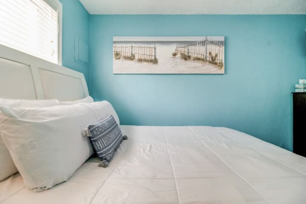 A bedroom with a bed, a window, and a wall-mounted picture.