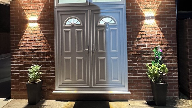 A brick building with a white double door and two potted plants on either side. - Royal Modern Studio Heathrow London (Feltham)