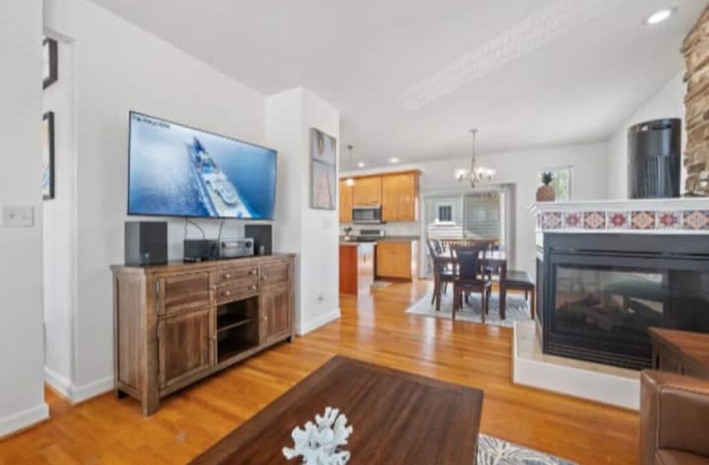 A modern living room with a flat-screen TV, wooden entertainment unit, and a fireplace.