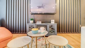 Una sala de estar moderna con un televisor de pantalla plana en la pared, una mesita con un recipiente de bocadillos y un sofá.