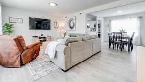 A modern living room with a sofa, a coffee table, and a dining area with a table and chairs.