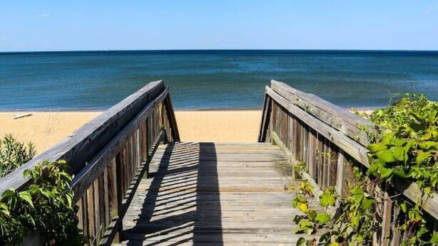 A wooden boardwalk leading to a beach with clear blue water.