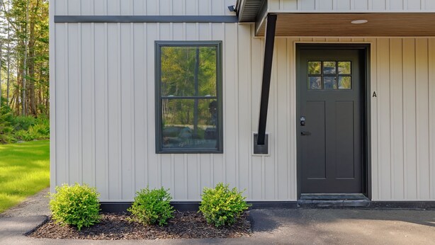 A modern building with a grey exterior, a black door, and a window. - Serene 2-bedroom apartment with WiFi in Ellsworth with a backyard stream. (Ellsworth)
