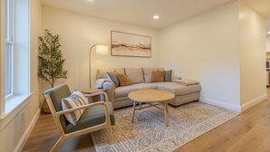 A modern living room with a sofa, a coffee table, and a chair. There is a plant, a lamp, and a painting on the wall. - Serene 2-bedroom apartment with WiFi in Ellsworth with a backyard stream. (Ellsworth)