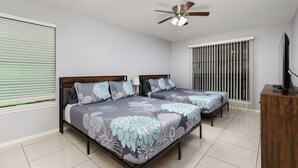 A bedroom with two beds, a ceiling fan, and a TV on a wooden cabinet. - The 3 Queen Suite by 802 & Paredes (Brownsville)