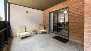 A covered patio area with two wicker chairs and a small table. - The 3 Queen Suite by 802 & Paredes (Brownsville)
