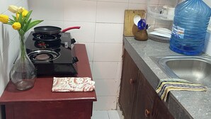 Une cuisine équipée d’une cuisinière, d’un évier, d’un grand distributeur d’eau et d’un vase rempli de fleurs jaunes.