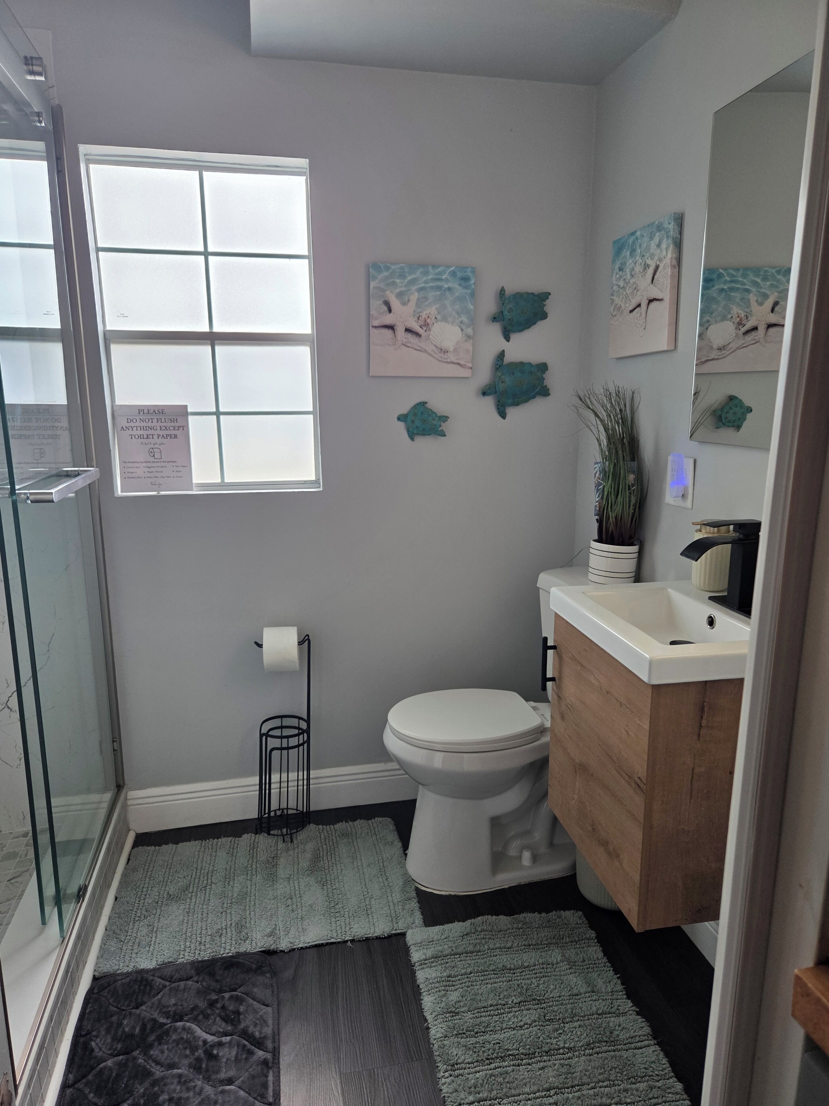 Un baño con ducha, inodoro, lavabo y ventana.