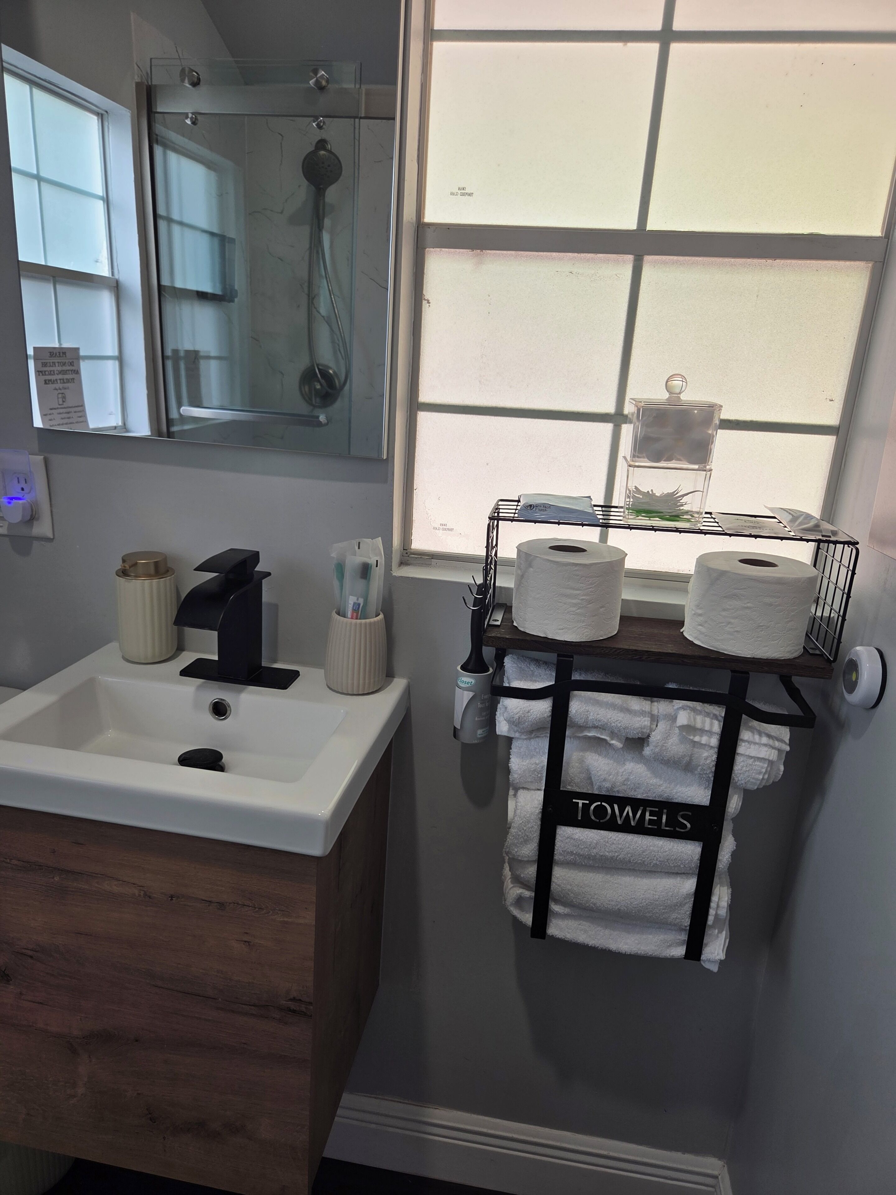 A bathroom with a sink, mirror, towel rack, and a shower.