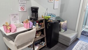 A compact living space with a TV, coffee maker, and a small fridge. There are signs for WiFi and no smoking.