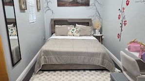 A bedroom with a bed, a desk, a chair, a mirror, and wall decorations.