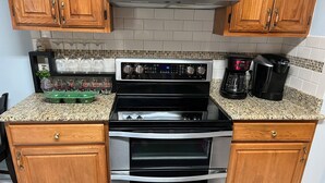 A kitchen with wooden cabinets, a stainless steel stove, an oven, and a coffee maker. - Large home near the ocean, sleeps 1-11 guest! (Navarre)
