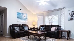 A spacious living room with two leather sofas, a coffee table, and a patterned rug. - Large home near the ocean, sleeps 1-11 guest! (Navarre)