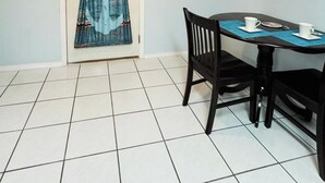 A dining area with a table and chairs, a tiled floor, and a wall-mounted power outlet. - Large home near the ocean, sleeps 1-11 guest! (Navarre)